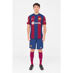Man wearing Lamine Yamal Barcelona jersey with blue and red stripes, paired with matching shorts and socks